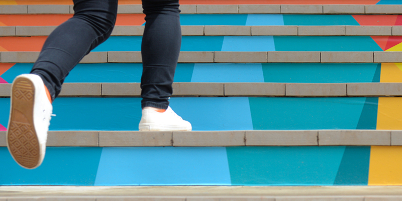 En person går upp för färgstarka trappor